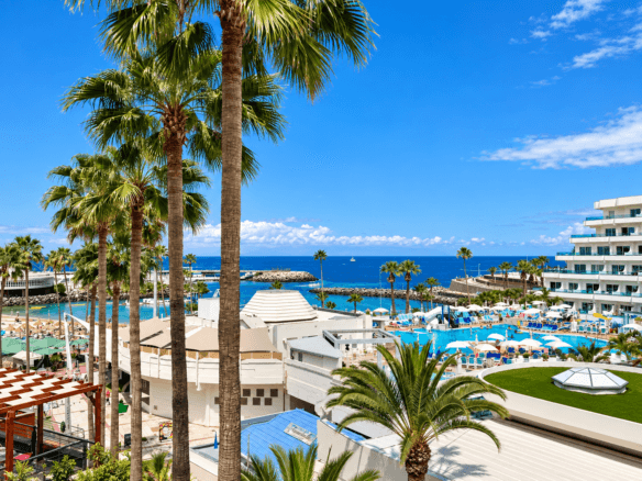 Sea-view from a family show bar in Puerto Colón, Costa Adeje, Tenerife, with palm trees, resort pools and coastal views