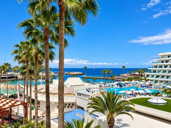 Sea-view from a family show bar in Puerto Colón, Costa Adeje, Tenerife, with palm trees, resort pools and coastal views