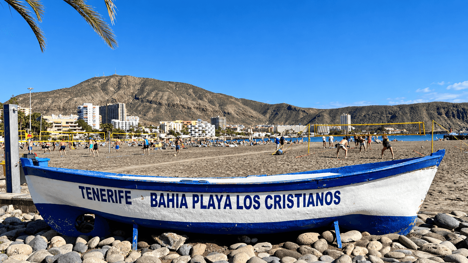 Los Cristianos area guide featured image showing the beach, traditional boat and mountains in Tenerife