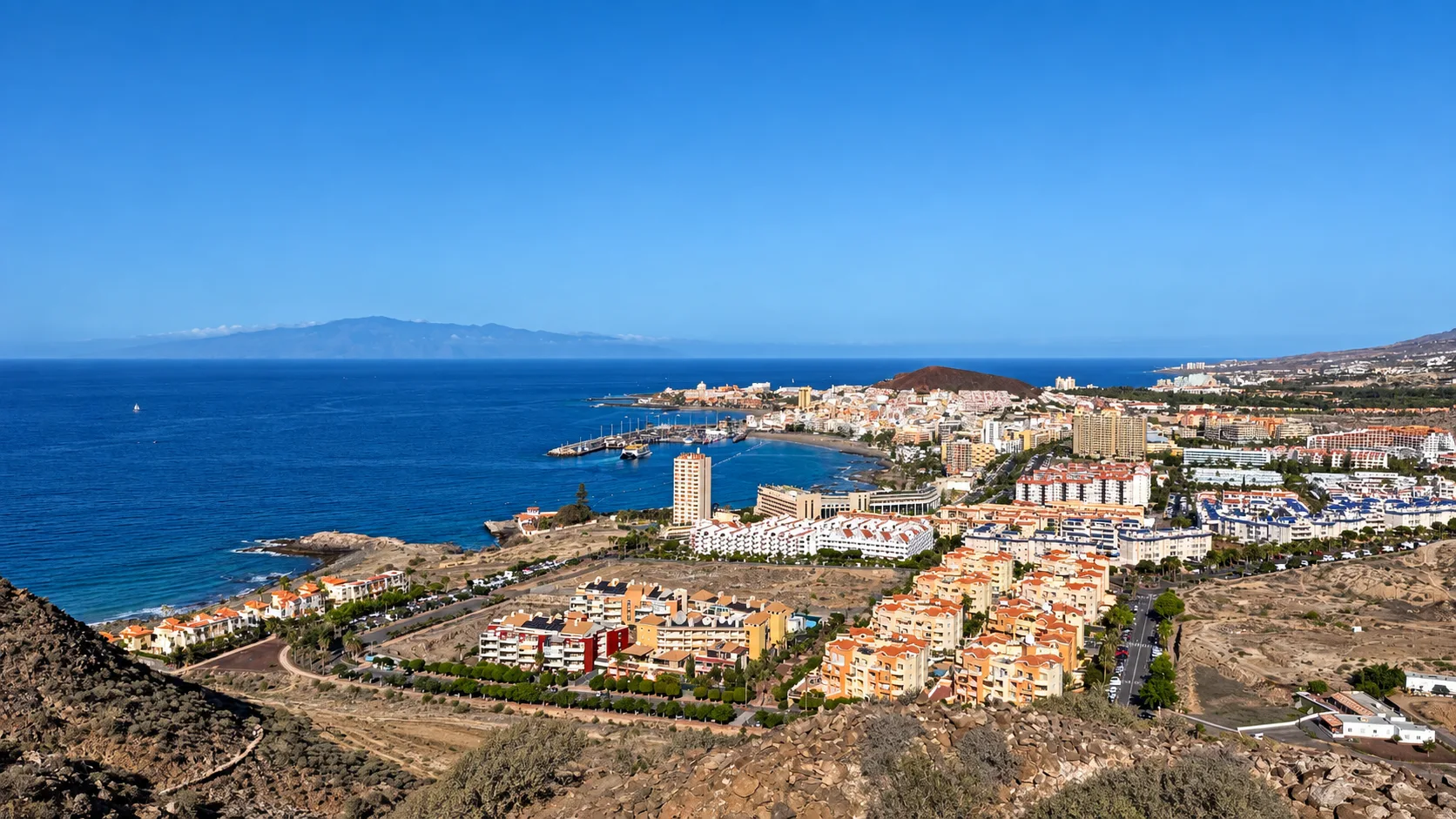 Elevated view over Los Cristianos in Tenerife showing the coastline, harbour and town